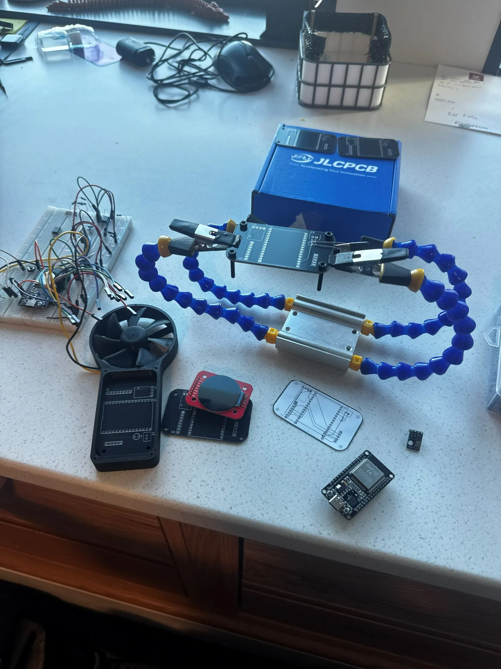 Bench build — the printed anemometer body, the fabricated control boards from JLCPCB, an ESP32 dev board, and a breadboard of test wiring.