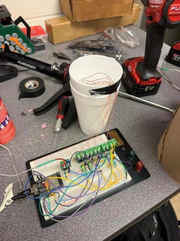 Thermocouple calibration setup — six type-K probes taped into a styrofoam cup of ice water, wired to a breadboard carrying six green MCP9600 amplifier breakouts and an ESP32.