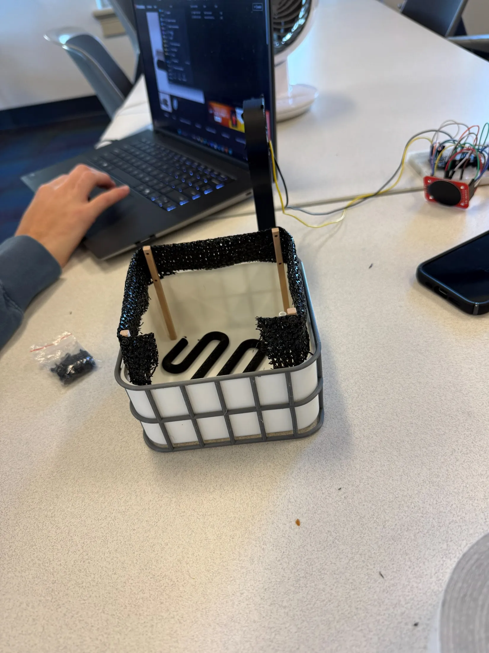The 3D-printed microfarm with black wind mesh stretched across its top frame on printed posts.